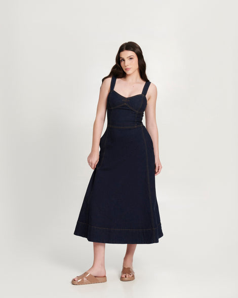 Model in a black dress wearing a pair of brown Cozy Cross sandals with crisscross top straps