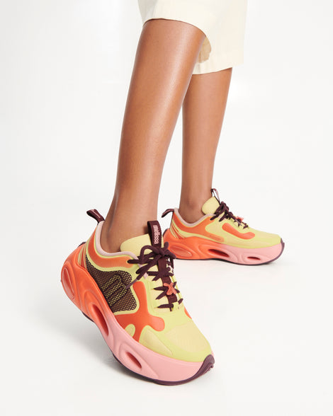 Model's legs wearing a pair of orange/green/pink X Loop sneakers