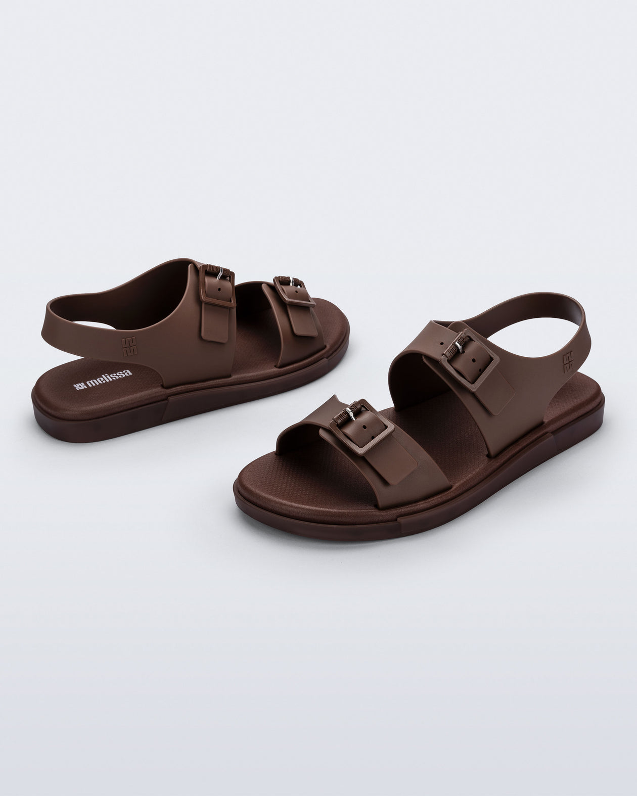 Side and angled view of a pair of brown Wave Sandals with two straps with buckles and a back strap