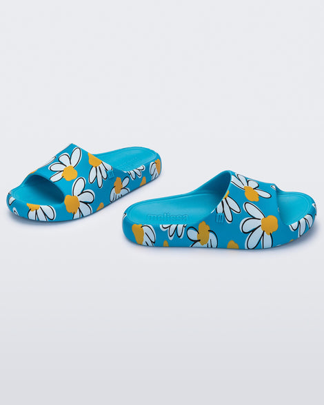 Angled view of a pair of blue Free Print Slides with daisy print flowers