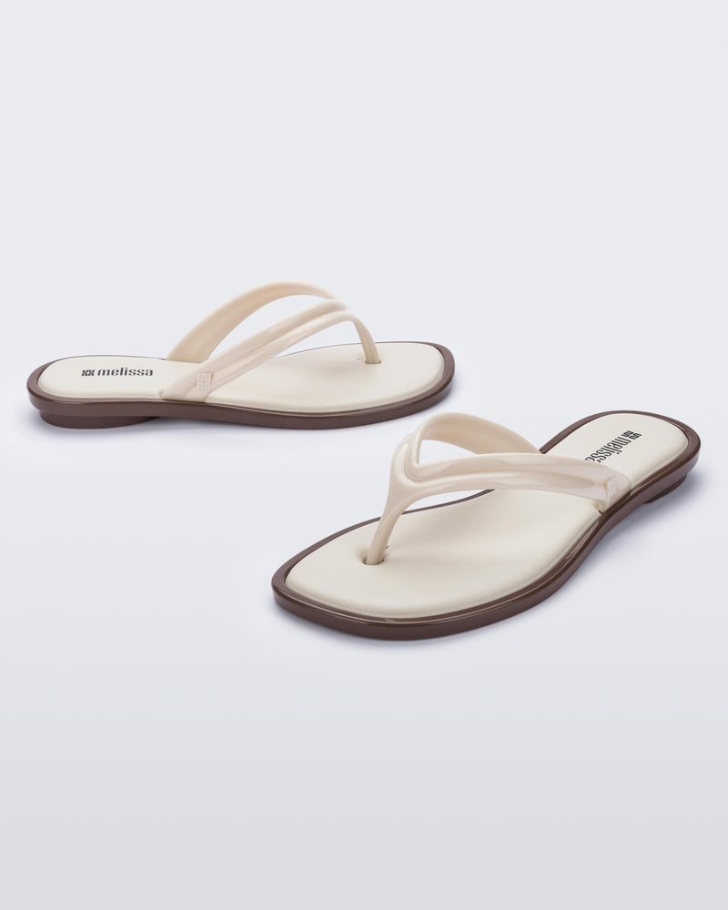 Side and angled view of a pair of beige Wave Flip Flops with small heel and brown sole