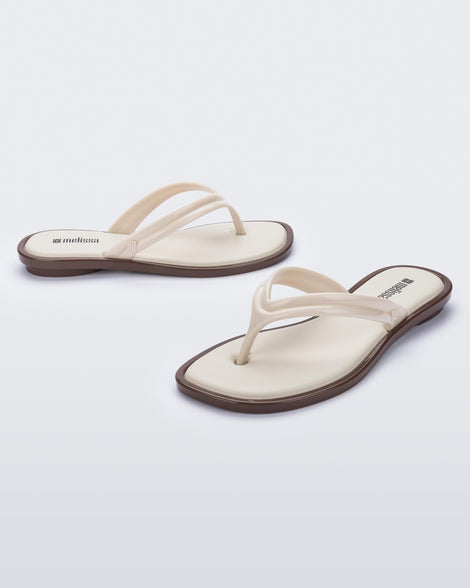 Side and angled view of a pair of beige Wave Flip Flops with small heel and brown sole