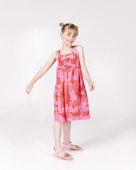 Chicd model in a pink and red patterned dreas wearing a pair of pink Mar Wave kids sandals.