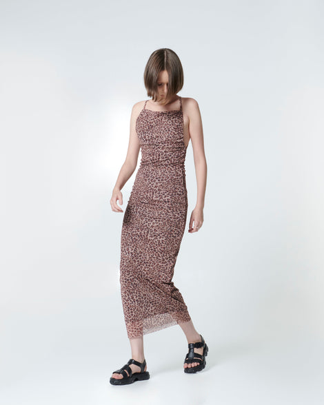 Model in an animal print dress wearing a pair of black Ella sandals