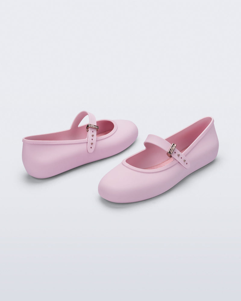 Side and front angled view of a pair of pink Soft Ballerina flats with top buckle strap