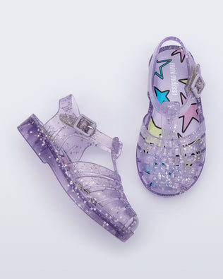Side and top view of a pair of clear lilac Possession baby sandals with star glitter