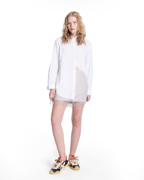 Model in a white outfit wearing a pair of black and beige X Bend sneakers with yellow sole