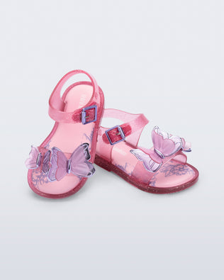 Angled view of a pair of glitter pink baby Butterfly sandals with pink butterflies