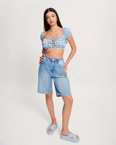 Model in a jean shorts and blue top wearing a pair of blue Cozy Cross platform sandals with crisscross top straps