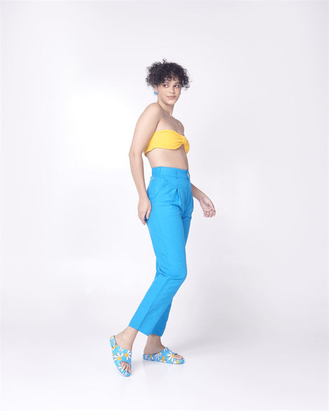 Model in blue pants and a yellow top wearing a pair of blue Free Print Slides with daisy print flowers