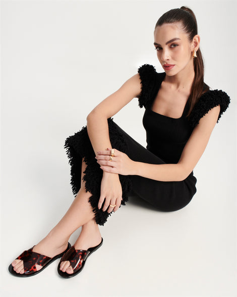 Model in a black dress wearing a pair of black Essential Cross Slide sandals with tortoise colored straps
