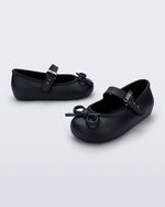 Side and angled view of a pair of black Soft Ballerina Delicate Bow baby flats with top strap and bow