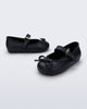Side and angled view of a pair of black Soft Ballerina Delicate Bow baby flats with top strap and bow