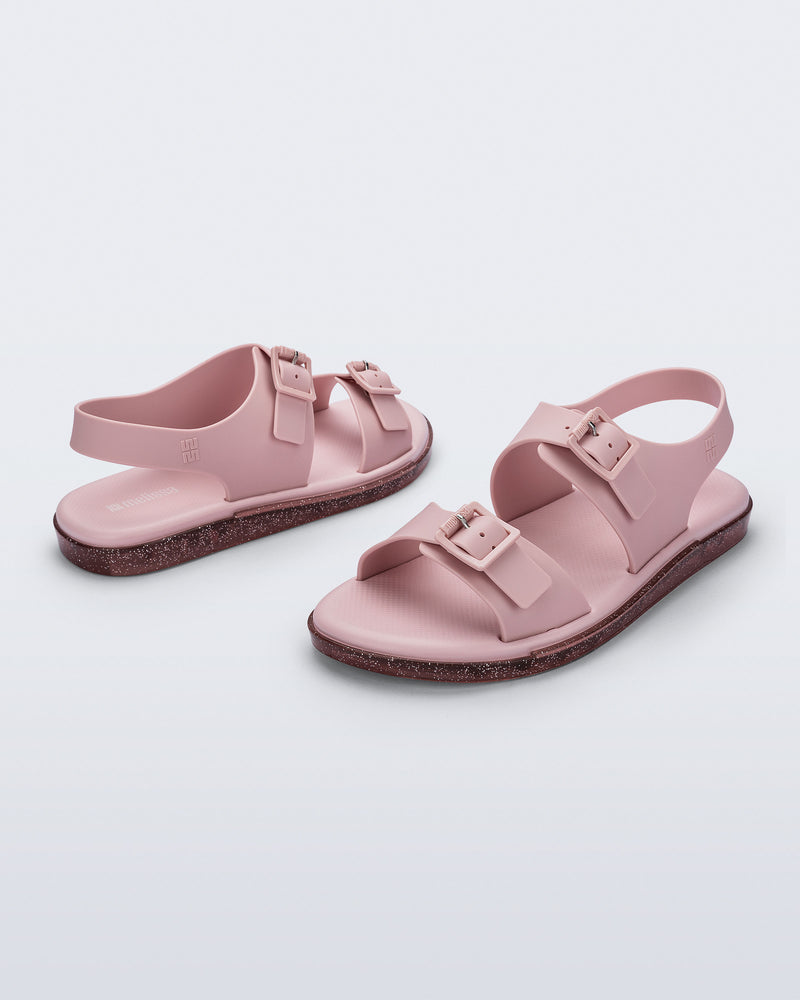 Side and angled view of a pair of pink Wave Sandals with two straps with buckles and a back strap
