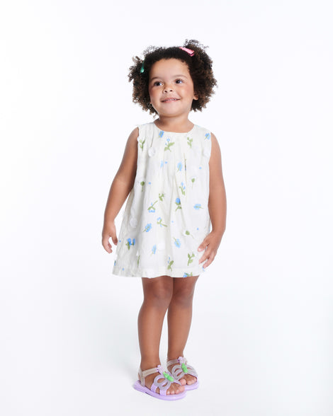 Child model in a white dress wearing a pair of lilac Hip Butterfly baby sandals