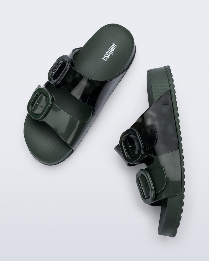 Side and top view of a pair of dark green Cozy slides with part clear green upper with 2 buckles