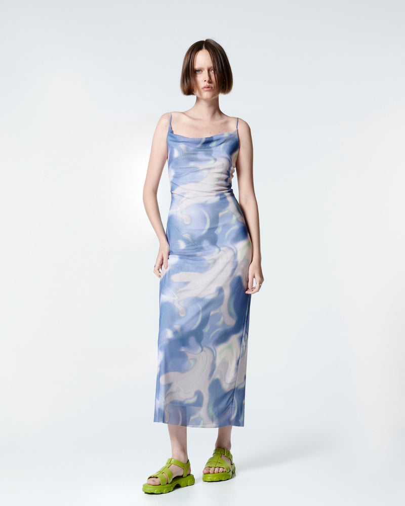 Model in a blue print dress wearing a pair of green Ella sandals