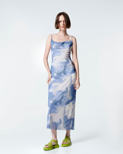 Model in a blue print dress wearing a pair of green Ella sandals