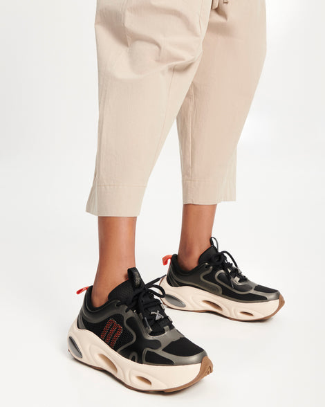 Model's legs wearing a pair of black X Loop sneakers with beige sole