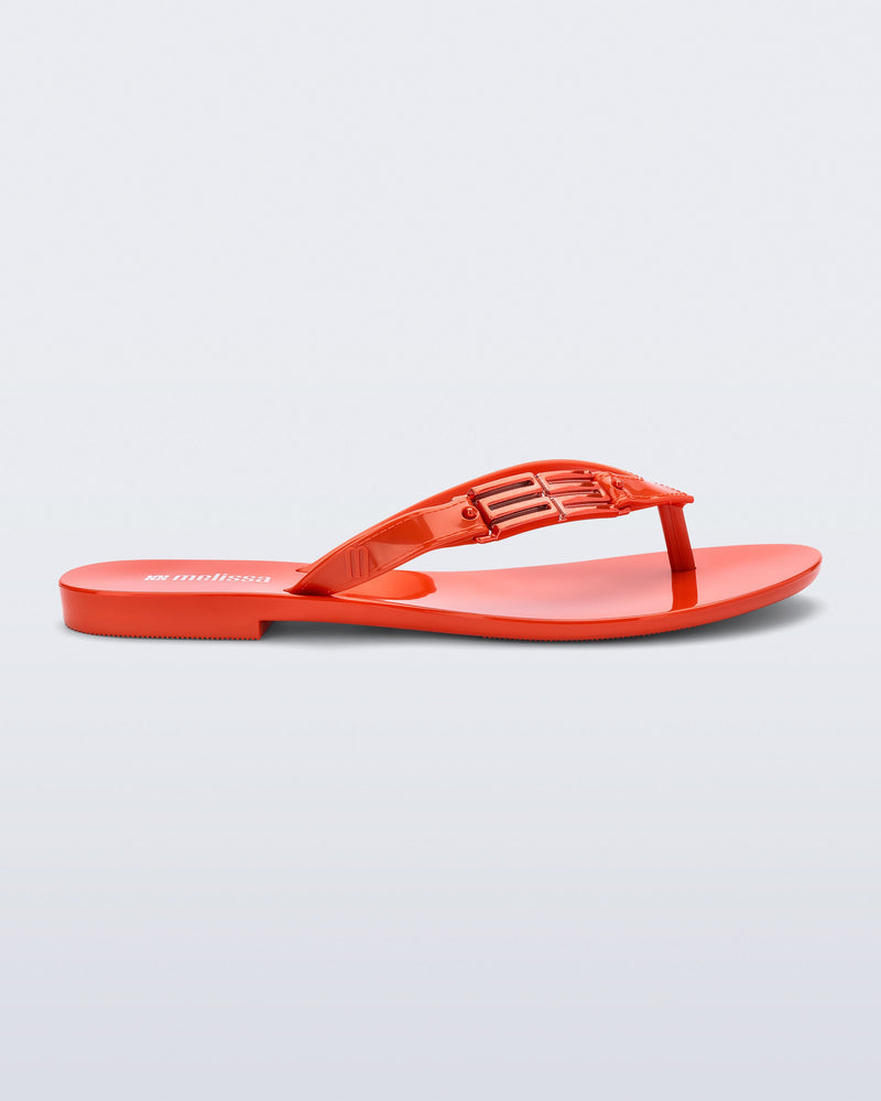 Side view of a red Harmonic M Chic flip flop