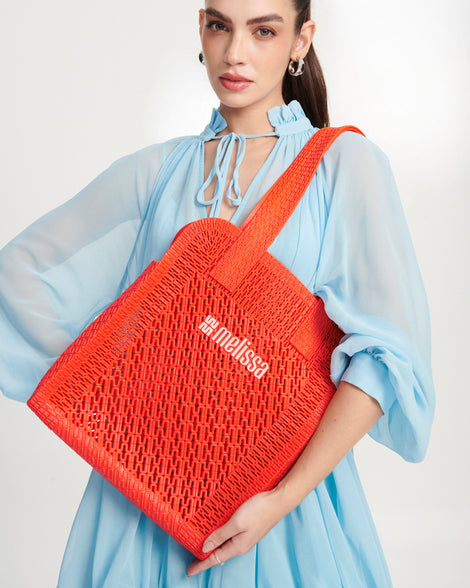 Model in a blue outfit with an orange Harper bag on her shoulder