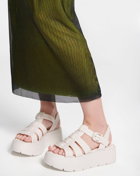Model's legs in a green skirt wearing a pair of light beige Up Platform sandals