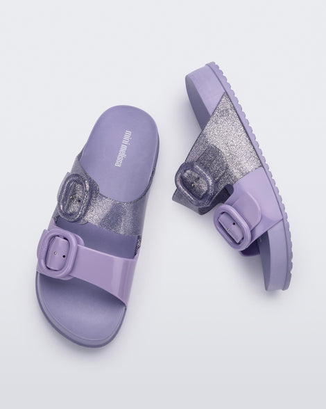 An top and side view of a pair of lilac Mini Melissa Cozy slides with two front straps with buckle details