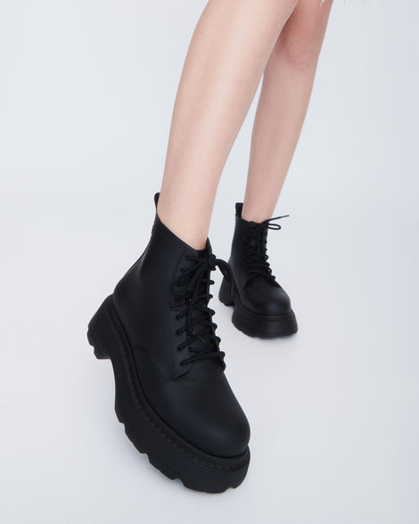 Model's legs wearing a pair of matte black Coturno Soft Platform boots
