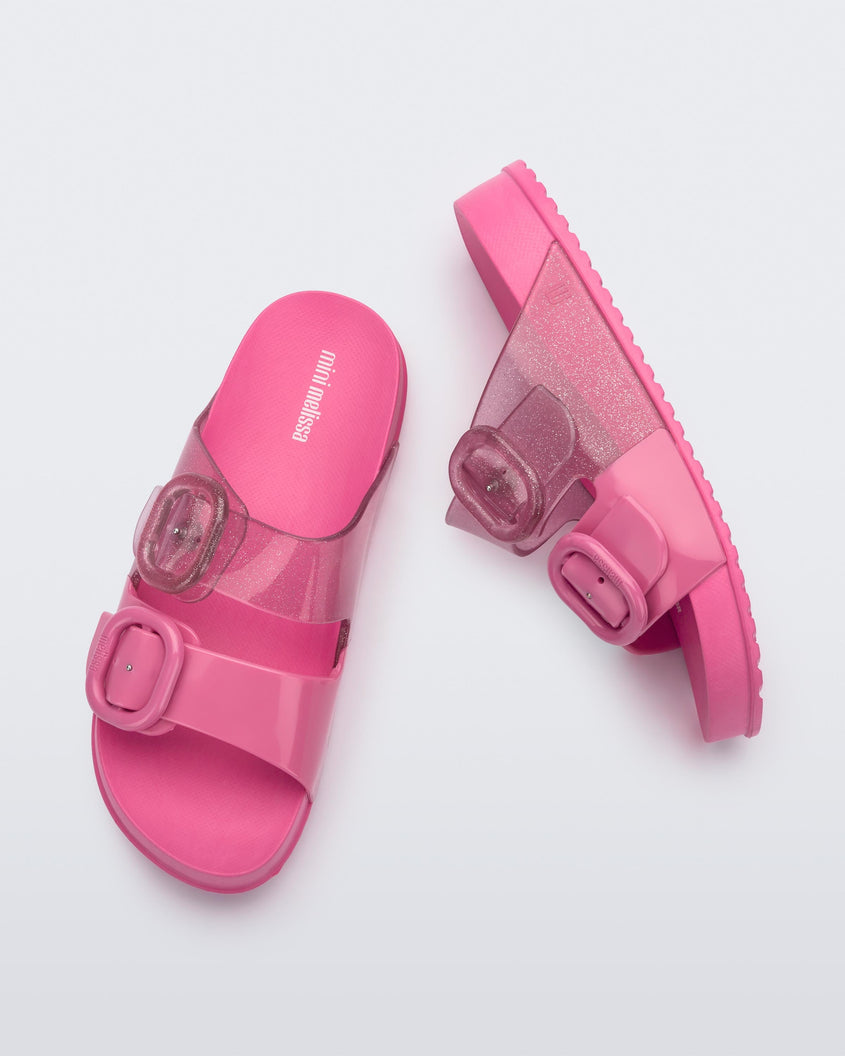 An top and side view of a pair of pink Mini Melissa Cozy slides with two front straps with buckle details