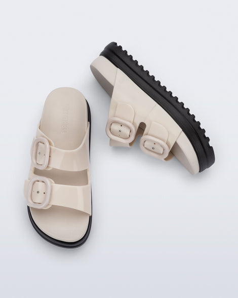 Side and top view of a pair of beige Cozy Platform kids slides with two straps with buckles and black sole