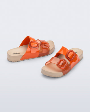 Angled view of a pair of orange Cozy slides with beige soles