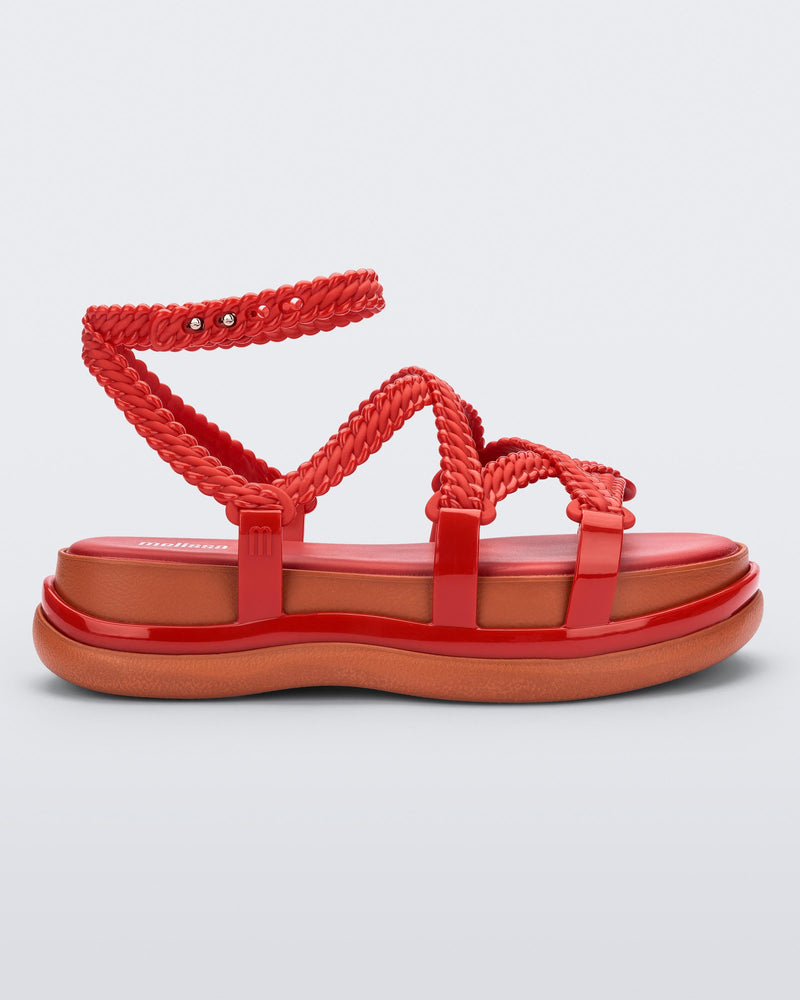 Side view of a red Melissa Buzios platform sandal with multiple textured straps that mimic sisal braids across the front of the shoe as well as an ankle strap