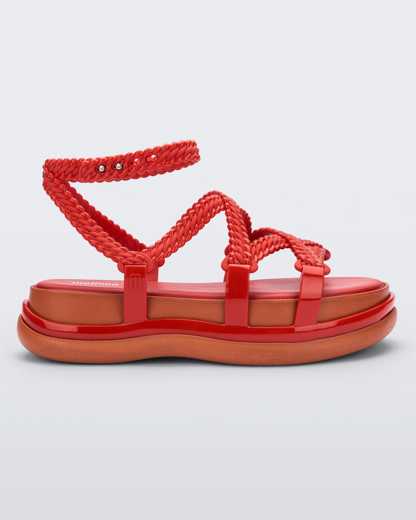Side view of a red Melissa Buzios platform sandal with multiple textured straps that mimic sisal braids across the front of the shoe as well as an ankle strap
