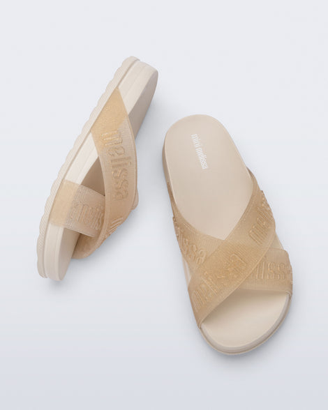 Side and top view of a pair of beige Cozy M Lover Slides with Melissa on the upper