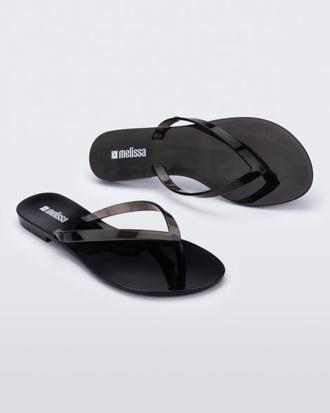 Angled and top view of a pair of clear black Harmonic Jelly flip flops