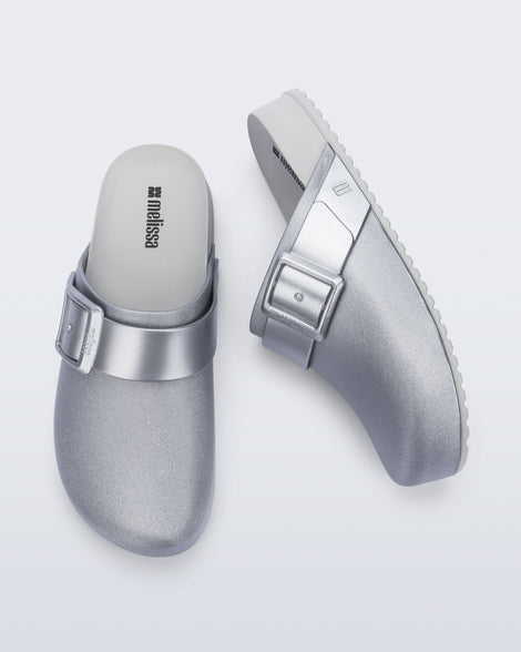 Side and top view of a pair of silver Cozy Clog with buckle decoration