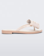 Side view of a Melissa slim strap flip flop in light beige with bow applique