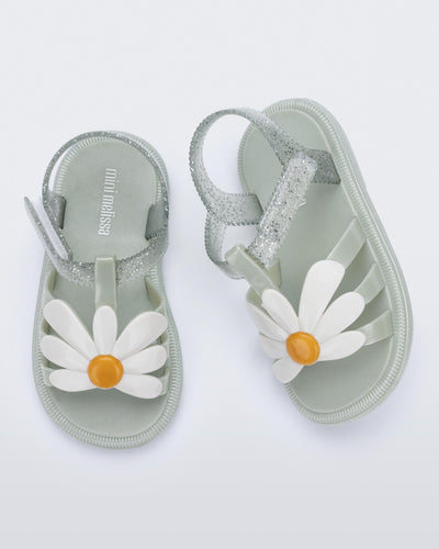 Top view of a pair of metallic green Hip Bloomy baby sandals with white daisy on top