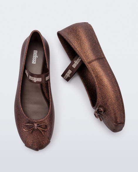 Top and side view of a pair of Melissa Sophie ballet flats in bronze with M-logo strap and bow applique