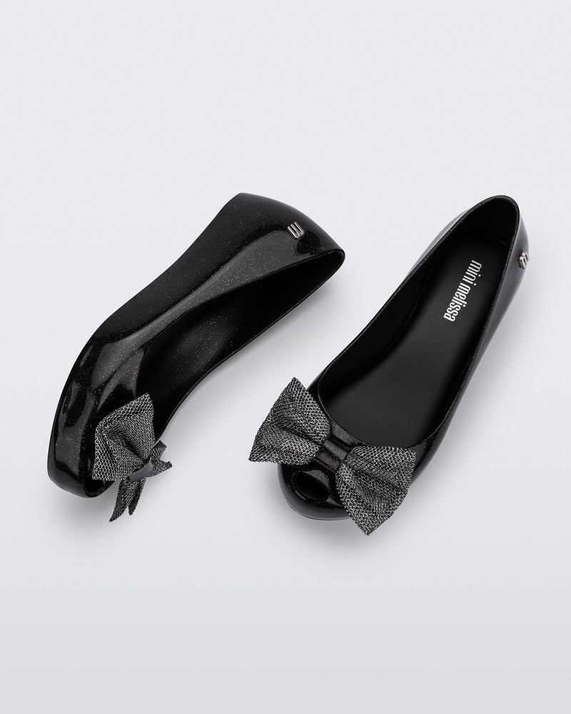 Top and side view of a pair of glitter black Ultragirl Sweet kids ballerina flats with bow