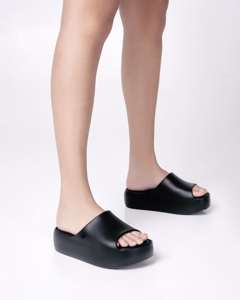 Model's legs wearing a pair of black Free Platform women's slides