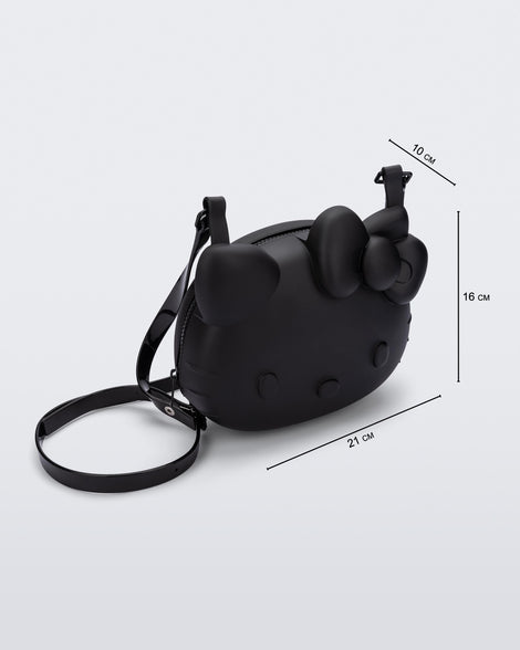 Angled view of a black Hello Kitty + Friends Cute Bag with the face of Hello Kitty with measurements 21cm x 10cm x 16cm