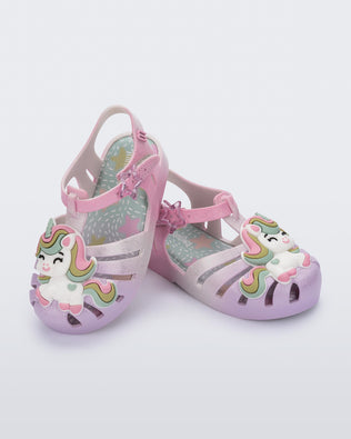Angled view of a pair of purple/pink Possession Unicorn baby sandals with unicorn on front upper