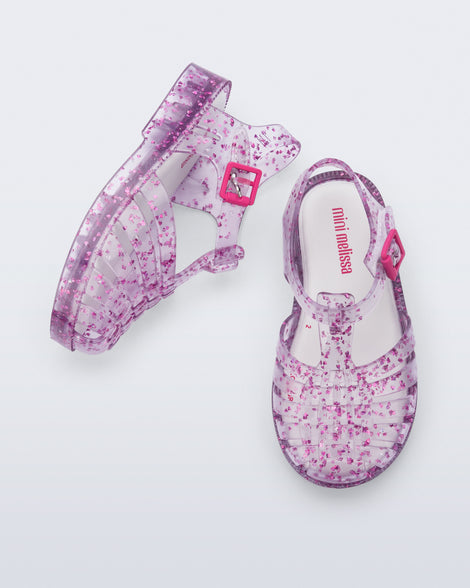 Top and side view of a pair of clear Possession Elements baby sandal with pink glitter hearts