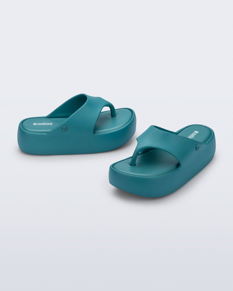 Side and angled view of a pair of teal Free Platform Thong