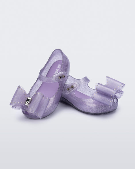 Angled view of a pair of glitter lilac Ultragirl Classic bow baby flats
