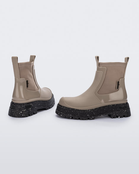 Side and back angled view of a pair of beige Drip Boots with black sole