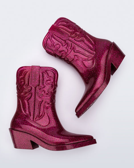 Side view of a pair of glitter pink Texas boots with pointed toe.