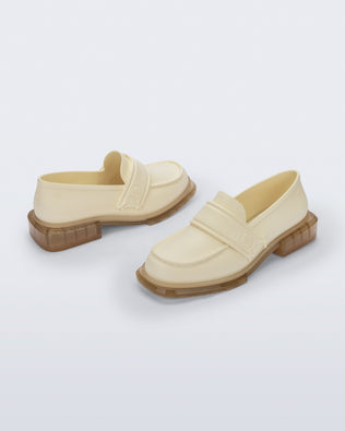 Back and angled view of a pair of beige Spencer loafers with clear beige soles