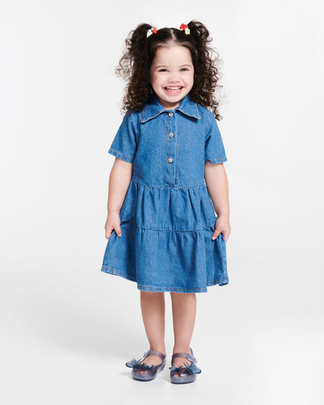 Child model in a blue dress wearing a pair of blue glitter Ultragirl Butterfly baby flats with butterflies on top